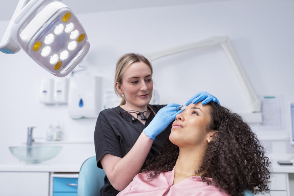 Cosmetic nurse injecting botox into patient in dental surgery