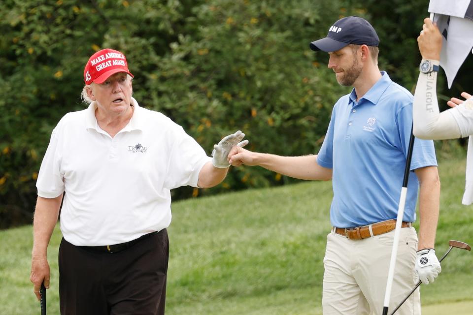 Former US president Donald Trump and son Eric Trump react to his putt on the 14th green during the pro-am prior to the LIV Golf Invitational - Bedminster at Trump National Golf Club Bedminster on 28 July 2022 (Getty Images)