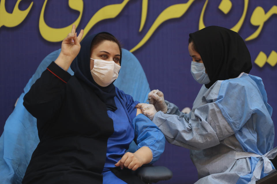 Sara Goudarzi, a nurse from the Imam Khomeini Hospital flashes a victory sign as she receives a Russian Sputnik V coronavirus vaccine in a staged event at Imam Khomeini Hospital in Tehran, Iran, Tuesday, Feb. 9, 2021. Iran on Tuesday launched a coronavirus inoculation campaign among healthcare professionals with recently delivered Russian Sputnik V vaccines as the country struggles to stem the worst outbreak of the pandemic in the Middle East with its death toll nearing 59,000. (AP Photo/Vahid Salemi)