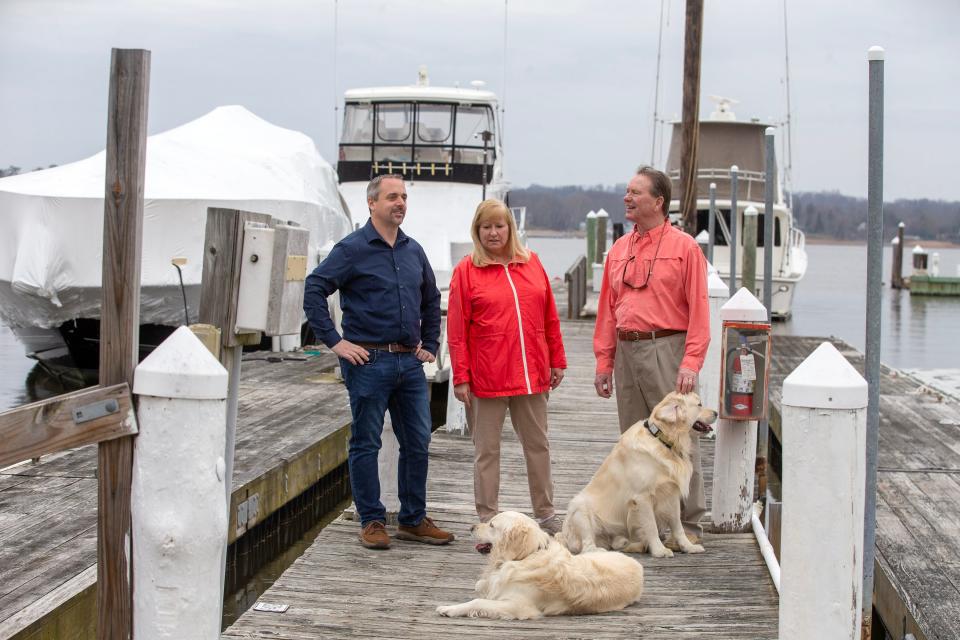 (right) Chan and (center) Christine Irwin, who have sold Irwin Marine, a marina on the Navesink River that has been in their family for 138 years, speak with (left) Tim Ryan, general manager of Irwin Marine Center, with their dogs, Connor and Jack, at Irwin Marine, which the new owners will name Irwin Marine Center, in Red Bank, NJ Thursday March 23, 2023.