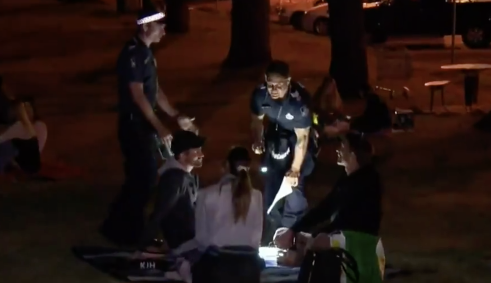 Pictured is a police officer speaking to three people sitting at the lookout.