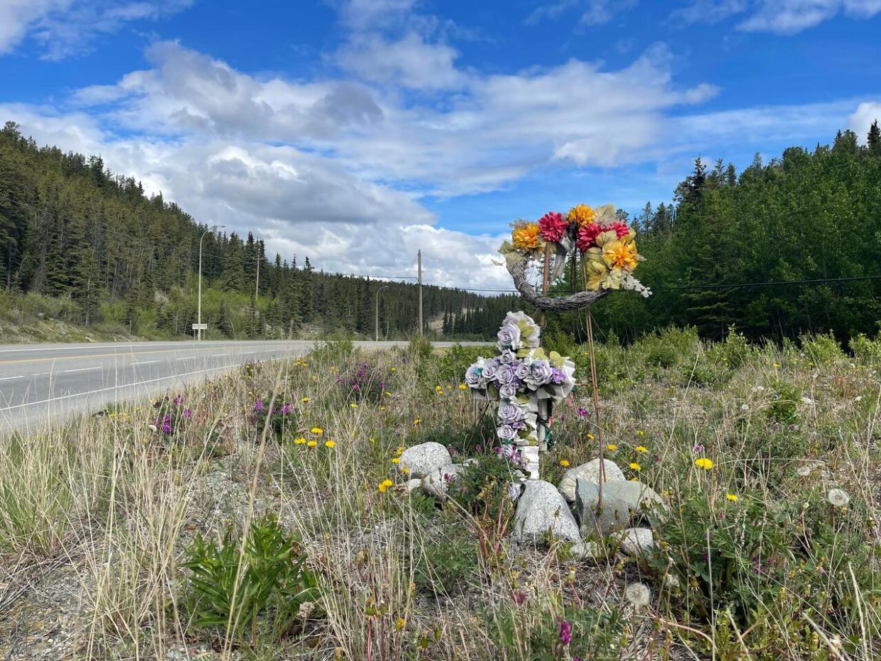 A memorial has been set up along the Alaska Highway, near where a cyclist was struck and killed by a vehicle on Thursday.  (Maria Tobin/CBC - image credit)