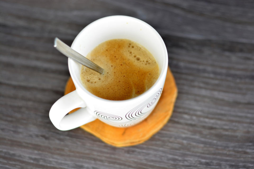 A cup of coffee with a spoon on a wooden surface