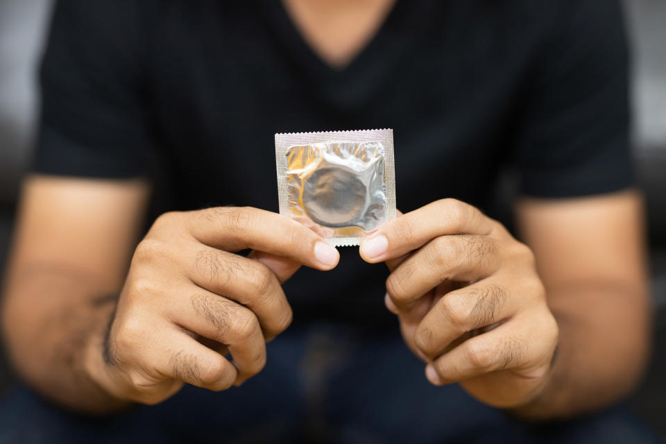 Two hands holding up a condom