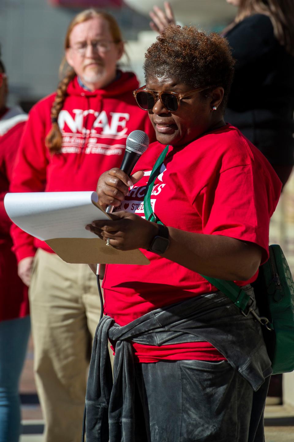 Cassandra Wells, an instructional assistant and bus driver, tells her story during a rally at Pack Square Park March 20, 2023.