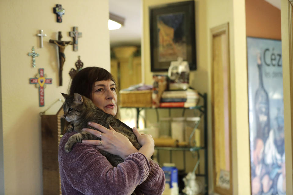 In this Jan. 10, 2020 photo, Genette Hofmann holds her cat Dottie in her home in Burlington, Wash., a few days before undergoing brain surgery in Seattle in hopes of reducing the epileptic seizures that had disrupted her life for decades. At the same time, Hofmann agreed to donate a small bit of her healthy brain tissue to researchers, who were eager to study brain cells while they were still alive, joining a long line of epilepsy patients who've helped scientists reveal basic secrets of the brain. (AP Photo/Ted S. Warren)