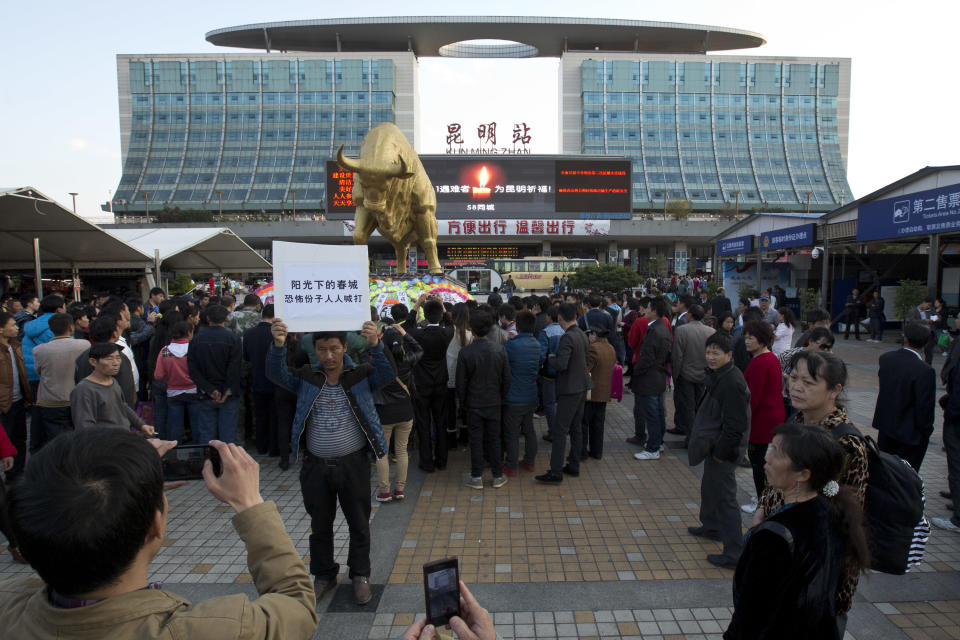 In this Monday, March 3, 2014 photo, a man holds a poster with slogans urging fights against terrorists on a square outside the Kunming Train Station, where more than 10 assailants slashed scores of people with knives Saturday evening, in Kunming, in western China's Yunnan province. China said the vicious slashing spree Saturday that killed 29 people in the southern city was the work of separatists linked to international terrorism, but the assailants’ homespun methods and low-tech weapons - nothing more than long knives - have led some analysts to suspect they didn’t get outside help. (AP Photo/Alexander F. Yuan)