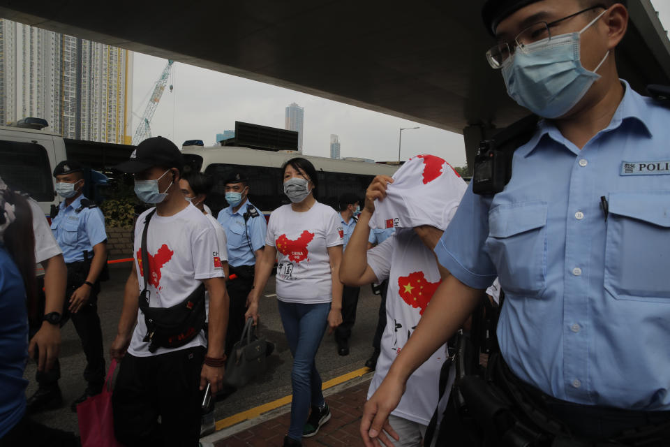 Pro-China activists are escorted by police officers as they argue with pro-democracy protesters outside a court during a protest in Hong Kong, Thursday, Aug. 27, 2020. Hong Kong police arrested 16 people, including two opposition lawmakers, on Wednesday on charges related to anti-government protests last year. (AP Photo/Kin Cheung)