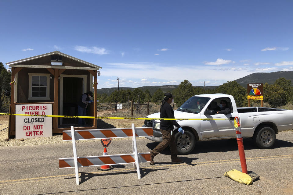 Members of the Native American community of Picuris Pueblo, N.M., including Vaughn Tootsie, right, screen vehicles as they enter and exit tribal property Thursday, April 23, 2020. Pueblo leaders including Gov. Craig Quanchello see COVID-19 as a potentially existential threat to the tribe of roughly 300 members and have implemented universal testing for infection. (AP Photo/Morgan Lee)