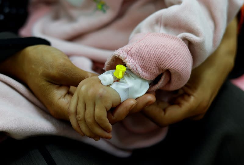 Israa, a malnourished Palestinian girl who is quadriplegic and epileptic, is held by her mother Umm Mesbah Heji in Rafah in the southern Gaza Strip