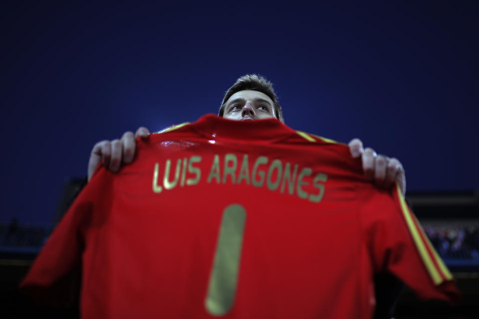 Atletico's fan displays a Spanish national t-shirt reading "Luis Aragones" during a minute of silence in memory of Luis Aragones prior to Spanish La Liga soccer match between Atletico de Madrid and Real Sociedad at the Vicente Calderon stadium in Madrid, Spain, Sunday, Feb. 2, 2014. (AP Photo / Andres Kudacki)