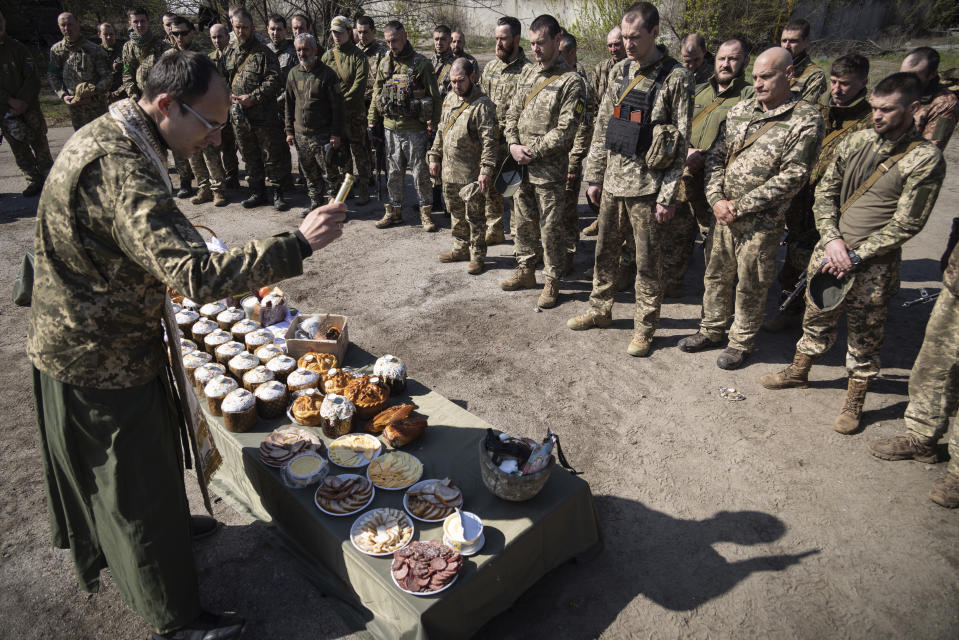 Un sacerdote militar ortodoxo bendice la comida tradicional durante la celebración de la Pascua para la brigada 128 del ejército ucraniano, el domingo 24 de abril de 2022, cerca de Zaporiyia, Ucrania. (AP Foto/Andriy Dubchak)