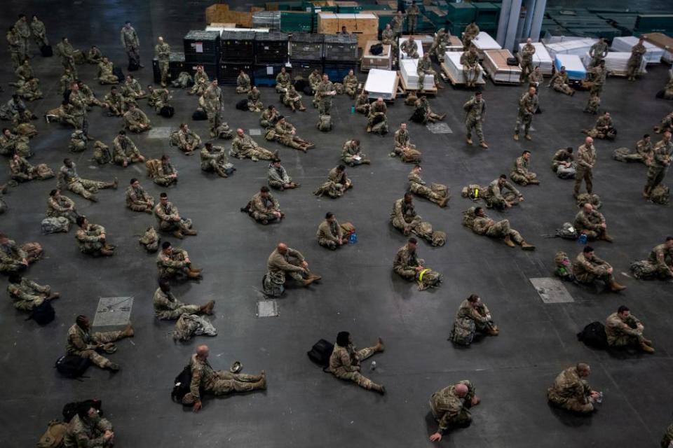 US Army personnel sit apart at the Jacob K Javits Convention Center in New York City, which will be partially converted into a hospital.