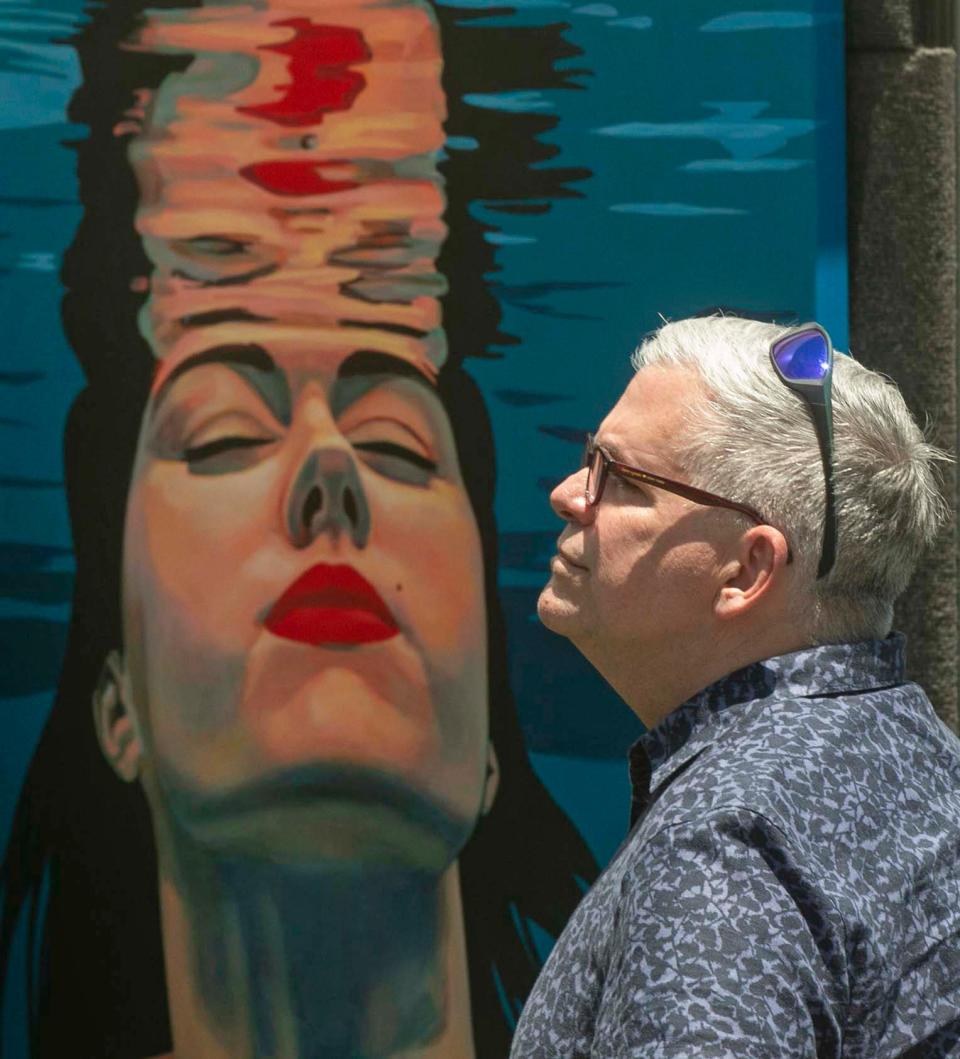 Mark Guidi, of Tampa, is juxtaposed by a painting by artist Pavlina Alea, of Atlanta, during the 49th annual Mayfaire by-the-Lake.