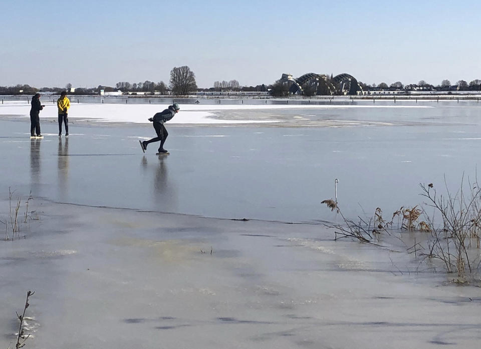 People skate on the ice of frozen flood plains of Nederrijn river near Doorwerth, Netherlands, Thursday, Feb. 11, 2021. The deep freeze gripping parts of Europe served up fun and frustration with heavy snow cutting power to some 37,000 homes in central Slovakia. (AP Photo/Aleksandar Furtula)