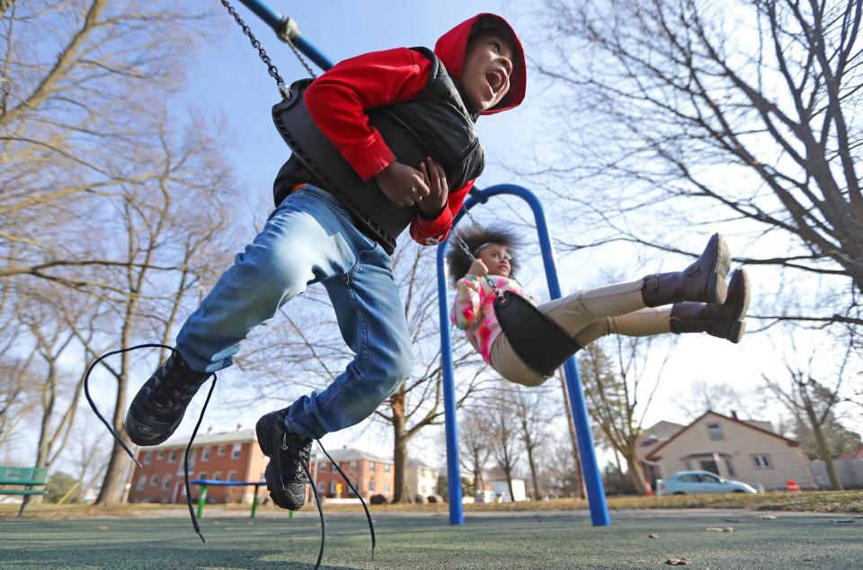 Elijah Williams, left, 4, and his sister Khamaya Williams, 7, play on the swings at Kern Park in Milwaukee on March 24, 2020.