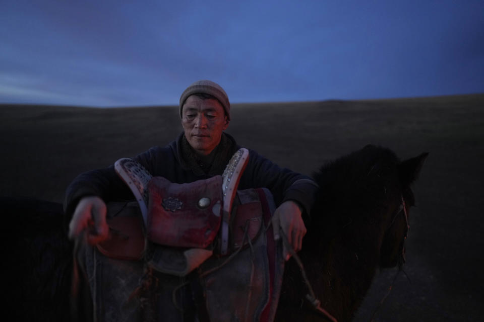 Herder Agvaantogtokh saddles a horse for his wife, Nurmaa, in preparation for a 24-kilometer (15-mile) journey with their livestock to a new location in the Munkh-Khaan region of the Sukhbaatar district, in southeast Mongolia, Sunday, May 14, 2023. (AP Photo/Manish Swarup)