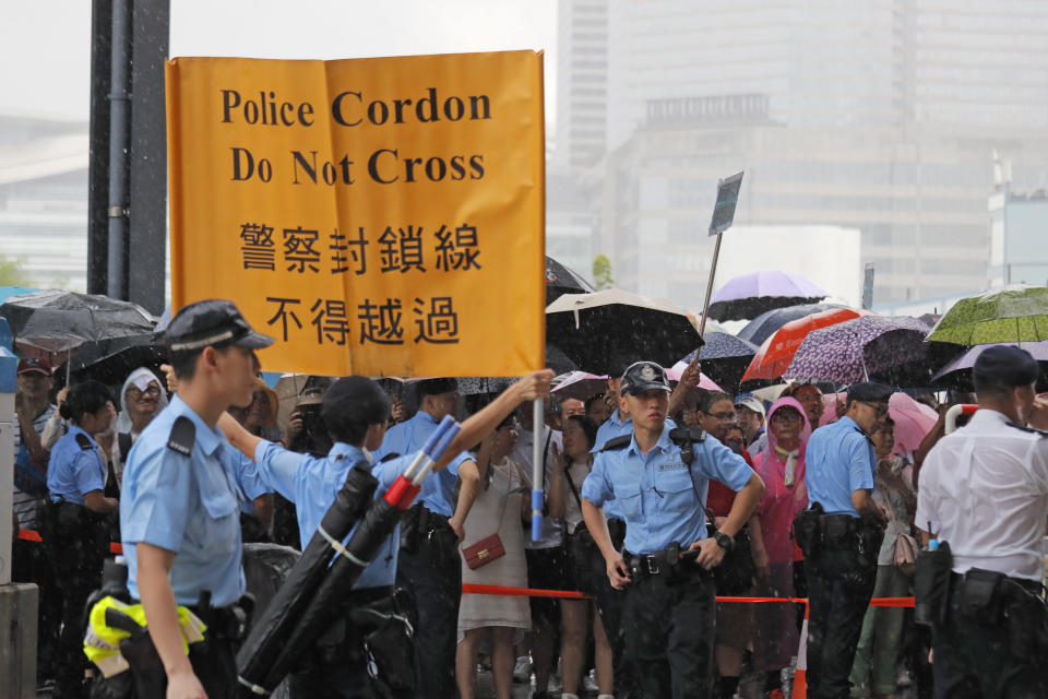 Police officers shows a warning banner to pro-China's supporters during a rally outside Legislative Council Complex in Hong Kong, Sunday, June 30, 2019. Pro-China's supporters rallied in support of the police at Tamar Park (AP Photo/Kin Cheung)