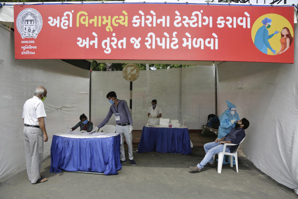 A health worker takes a nasal swab sample to test for COVID-19 in Ahmedabad, India, Monday, Sept. 14, 2020. India's coronavirus cases are now the second-highest in the world and only behind the United States. Banner in Gujarati reads, "Do Corona testing here free of charge and get report immediately". (AP Photo/Ajit Solanki)