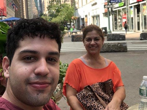 A man and a women smile at the camera. They are sitting at a table outside.