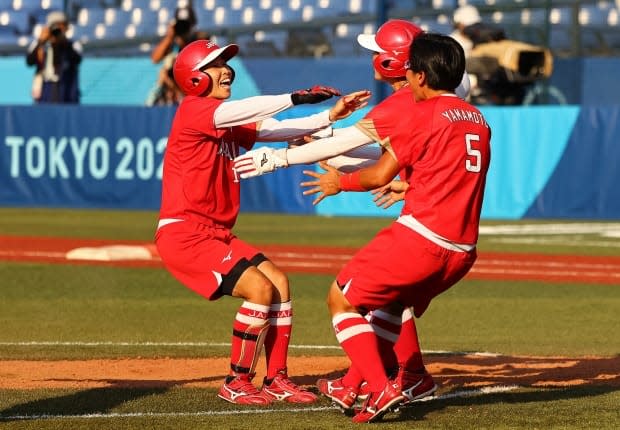 Member's of Japan's softball team celebrate after their 1-0 walk-off win in extra innings over Canada at the Tokyo Olympics on Sunday. (Jorge Silva/Reuters - image credit)