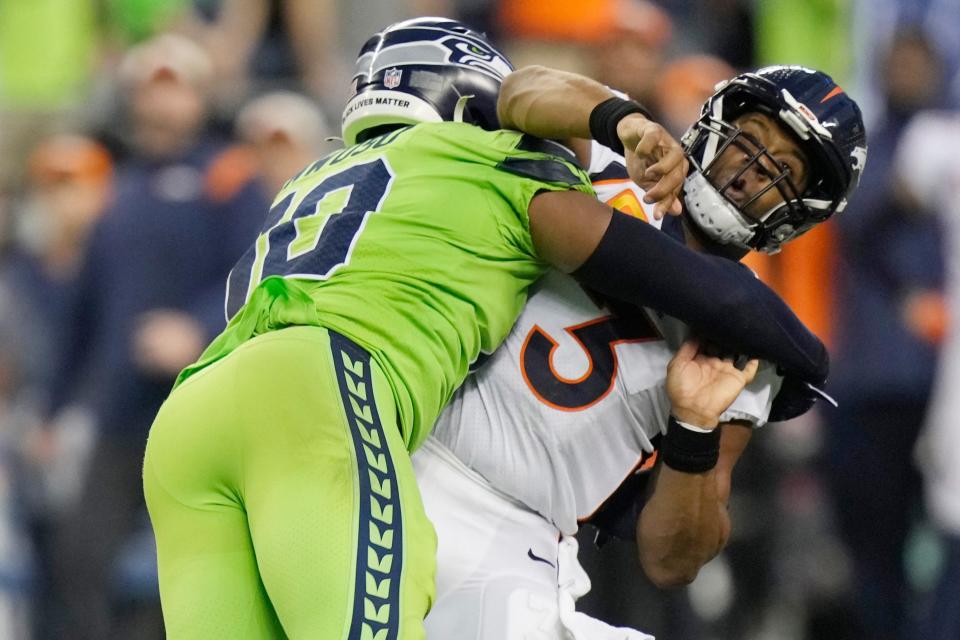 Denver Broncos quarterback Russell Wilson is hit by Seattle Seahawks linebacker Uchenna Nwosu.