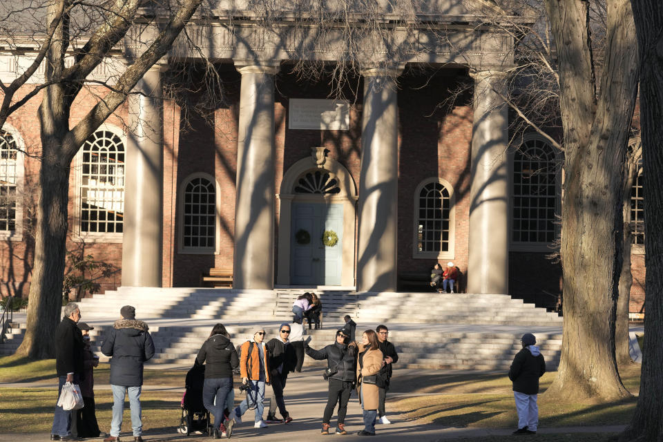 People pause for photographs, Tuesday, Jan. 2, 2024, on the campus of Harvard University, in Cambridge, Mass. Harvard University President Claudine Gay resigned Tuesday amid plagiarism accusations and criticism over testimony at a congressional hearing where she was unable to say unequivocally that calls on campus for the genocide of Jews would violate the school's conduct policy. (AP Photo/Steven Senne)