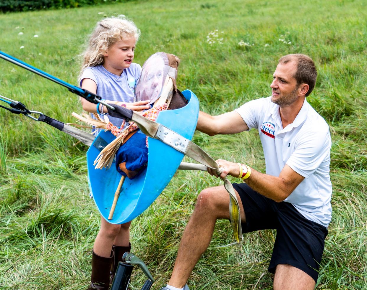 Ella Steen, age 8, helps her father Adam Steen load a Robin Vos dummy on a bungee slingshot on Monday August 8, 2022 in Burlington, Wis.