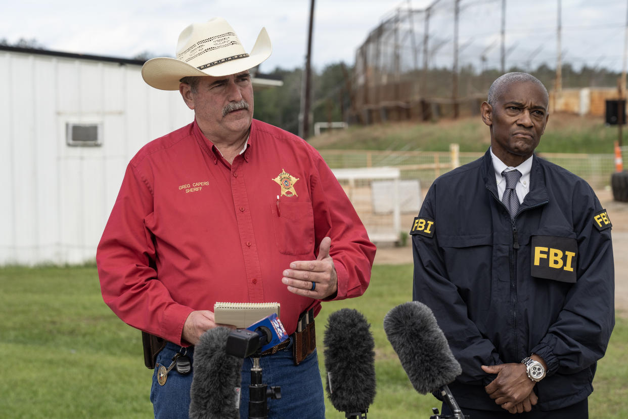 San Jacinto County Sheriff Greg Capers and FBI Special Agent in Charge James Smith stand outside near microphones.