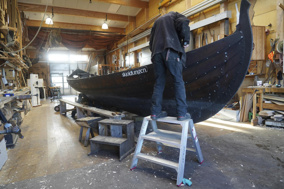 A man repairs a 10-meter wooden row boat, built in the Nordic clinker boat tradition, at the Viking Ship Museum's boatyard. Roskilde, Denmark, Monday, Jan. 17, 2022. For thousands of years, wooden sail boats, best known for having been in use during the Viking-era, allowed the peoples of northern Europe to spread trade, influence and -- in some cases war — across the seas and rivers. In December, UNESCO, the U.N.’s culture agency, added the “clinker’ boat traditions to its list of “Intangible Cultural Heritage,” the result of the first joint nomination from the whole Nordic region. (AP Photo/James Brooks)