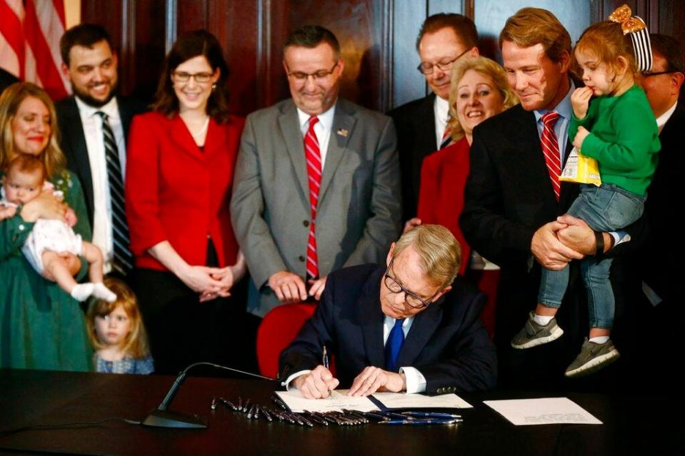 Gov. Mike DeWine speaks before signing a bill imposing one of the nation's toughest abortion restrictions, Thursday, April 11, 2019 in Columbus, Ohio. Lt. Governor Jon A. Husted stands at right holding Faye Zaffini, 2, the daughter of his chief of staff. DeWine's signature makes Ohio the fifth state to ban abortions after the first detectable fetal heartbeat. That can come as early as five or six weeks into pregnancy, before many women know they're pregnant. (Fred Squillante/The Columbus Dispatch via AP)