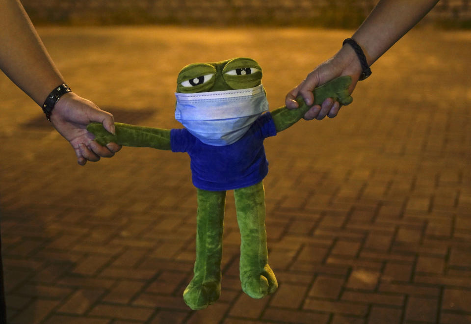 Protesters hold Pepe the frog plush toy, in Hong Kong, Friday, Oct. 18, 2019. Hong Kong pro-democracy protesters are donning cartoon/superheroes masks as they formed a human chain across the semiautonomous Chinese city, in defiance of a government ban on face coverings. (AP Photo/Vincent Yu)