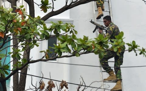Sri Lankan Special Task Force (STF) personnel climb a ladder outside a house during a raid  - Credit: &nbsp;ISHARA S. KODIKARA/AFP