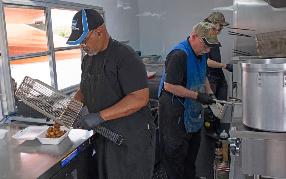 Michael Tice, John Wollschlaher, and Nick Gilpin fill lunch orders from the new Gulf Coast Seafood food truck on Thursday, Feb. 9, 2023. The new food truck operates from the old Gulf Coast Seafood location on Nine Mile Road.