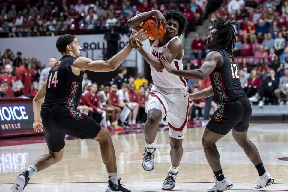 Alabama guard Davin Cosby Jr., center, attacks between Mercer forward TJ Grant (14) and guard David Thomas (12) during the first half of an NCAA college basketball game, Friday, Nov. 17, 2023, in Tuscaloosa, Ala. (AP Photo/Vasha Hunt)