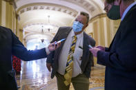 Sen. Jon Tester, D-Mont., peers around a doorway while speaking with reporters during a vote on amendments in the $1 trillion bipartisan infrastructure bill, at the Capitol in Washington, Tuesday, Aug. 3, 2021. (AP Photo/J. Scott Applewhite)