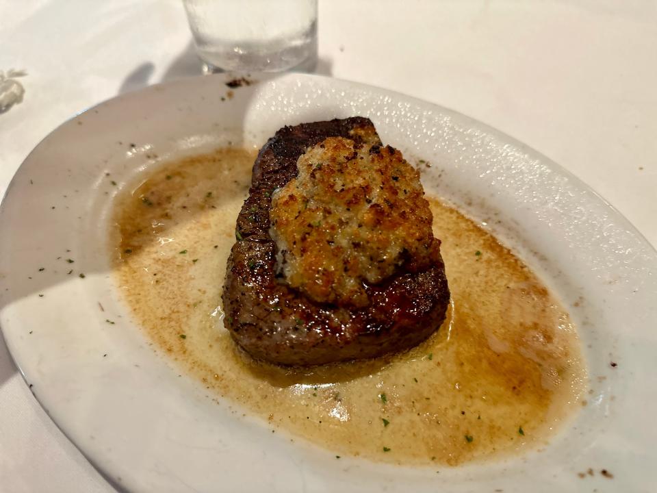 filet steak in pool of butter topped with golden-colored cheese