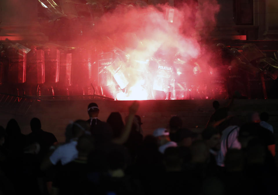 Protesters clash with riot police on the steps of the Serbian parliament during a protest in Belgrade, Serbia, Friday, July 10 2020. Hundreds of demonstrators tried to storm Serbia's parliament on Friday, clashing with police who fired tear gas during the fourth night of protests against the president's increasingly authoritarian rule. The protests started on Tuesday when President Aleksandar Vucic announced that Belgrade would be placed under a new three-day lockdown following a second wave of confirmed coronavirus infections. (AP Photo/Darko Vojinovic)