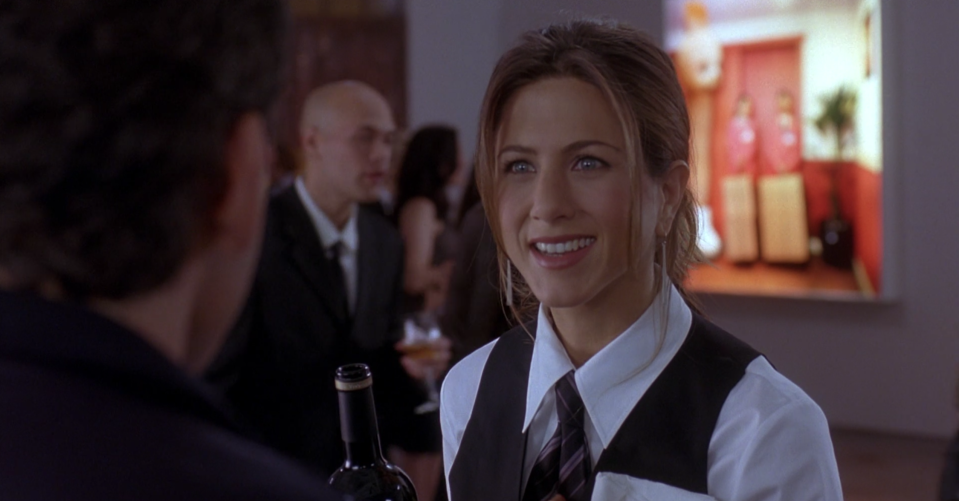 Jen wearing a tux and talking to Ben Stiller's character at a museum opening