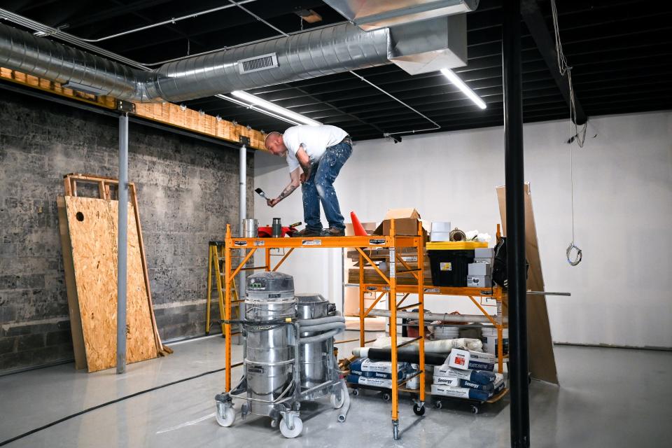 A painter works inside the Moneyball Sportswear's new headquarters on Tuesday, May 2, 2023, in Lansing.