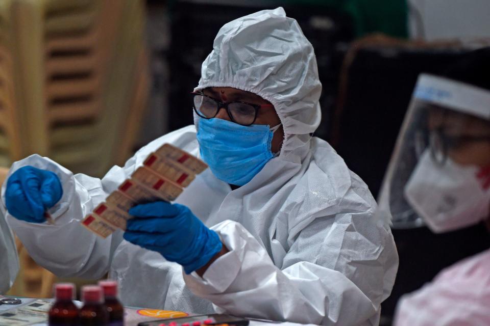 Medical volunteer distributes vitamin tablets in India, July 2020