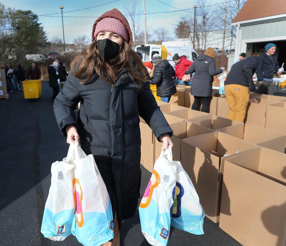 Timberland volunteer Michelle McWade carries food items to help fill Thanksgiving baskets for families at Operation Blessing in Portsmout Monday, Nov. 21, 2022.