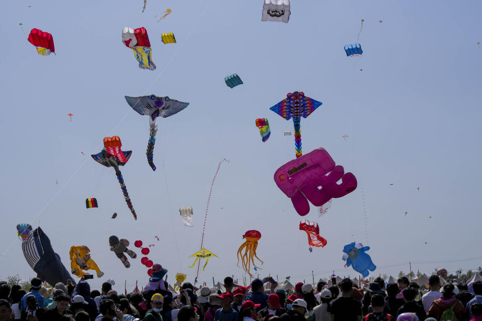 Visitors watch kites fly at the 41st International Kite Festival in Weifang, Shandong Province of China, Saturday, April 20, 2024. (AP Photo/Tatan Syuflana)