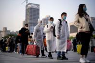 Travellers line up with their belongings outside Hankou Railway Station in Wuhan