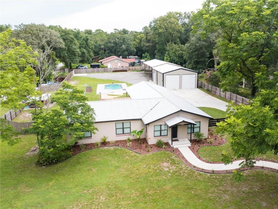 aerial view of a house for sale in florida with detached garage and pool in the background