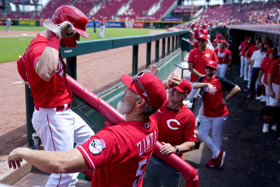 Cincinnati Reds right fielder Tyler Naquin (12) is congratulated by Cincinnati Reds hitting coach Alan Zinter (59) returning to the dugout after hitting a solo home run during the sixth inning of a baseball game against the Miami Marlins, Thursday, July 28, 2022, at Great American Ball Park in Cincinnati. 