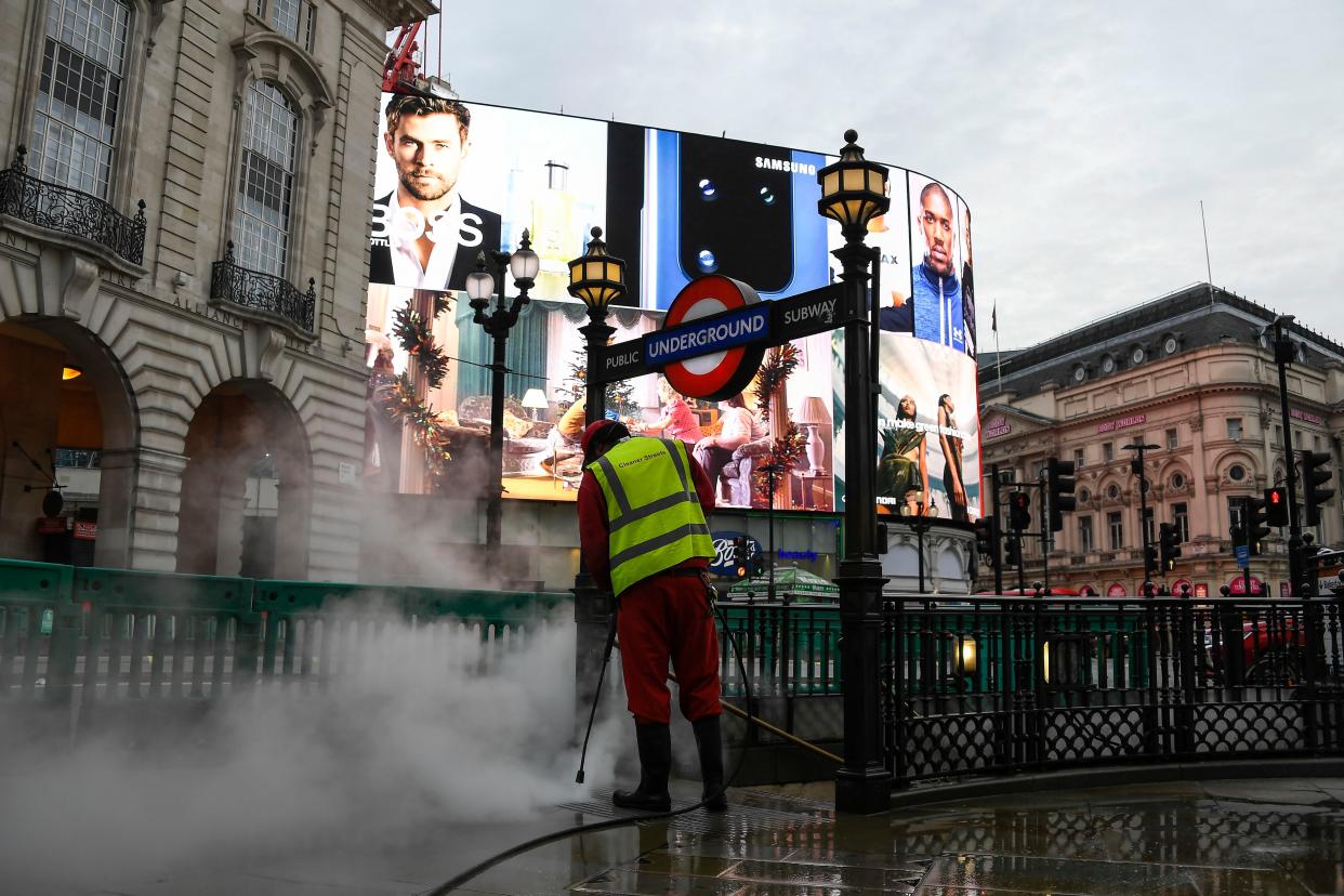 A street cleaner at work in Piccadilly Circus, London, on the first day after non-essential shops are allowed to reopen after England's second lockdown ended at midnight, due to the coronavirus outbreak, Wednesday, Dec. 2, 2020.