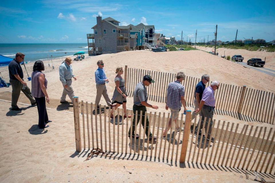 Robert Woodard, Chairman of the Dare County Commissioners, leads members of the NC 12 Task Force across the dunes at Mirlo Beach after a stop to survey the area on Tuesday, July 13, 2021 in Rodanthe, N.C.