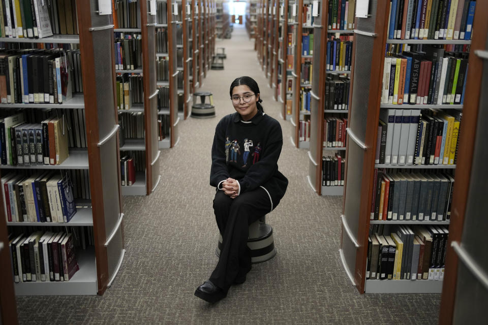 Gadi Hernandez-Corado, a student at UNLV, poses in a library at the university, Wednesday, April 12, 2023, in Las Vegas. Hernandez-Corado volunteers at an elementary school. (AP Photo/John Locher)