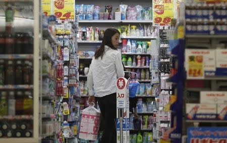 A shopper looks at items as she queues in line for the cashier at a discount store in Tokyo September 30, 2014. REUTERS/Yuya Shino